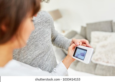 Parents Hold A Baby Monitor With Webcam To Monitor Their Baby