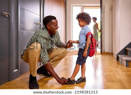 Parents At Home Helping Son Getting Ready To Go To School Putting On Shoes