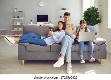 Parents and a kid child look at a laptop at their leisure in a weekend at home