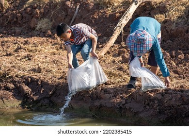 Parents And Kid Holding Plastic Bag Of Little Fish For Release The Fish To Pond