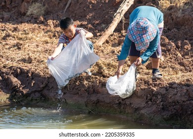 Parents And Kid Holding Plastic Bag Of Little Fish For Release The Fish To Pond