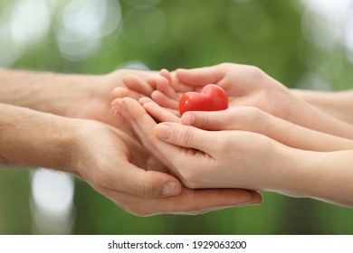 Parents And Kid Holding Red Heart In Hands Outdoors, Closeup. Family Day