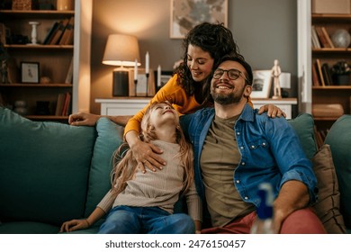 Parents and kid relaxing on a comfortable couch in their living room - Powered by Shutterstock