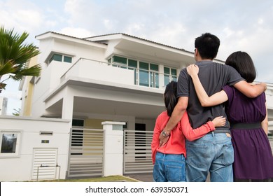 Parents And Kid Standing In Front Of Dream House In Modern Residential Houses