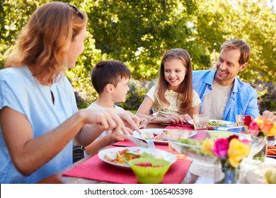 Parents And Kids Having A Lunch Together In The Garden