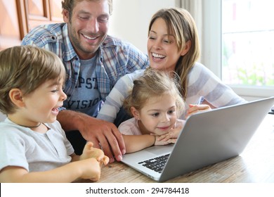 Parents With Kids At Home Using Laptop Computer