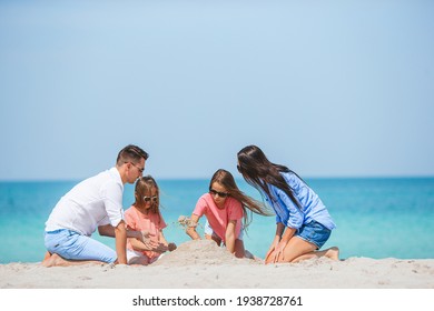 Parents And Kids Making Sand Castle At Tropical Beach. Family Playing With Beach Toys