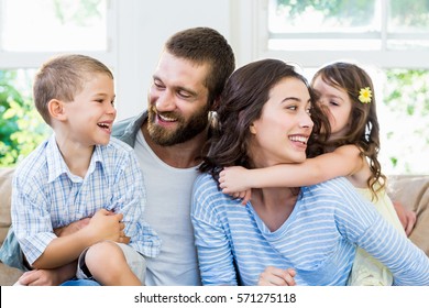 Parents and kids sitting on sofa and having fun at home
