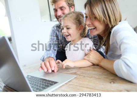 Parents with little girl laughing in front of laptop computer