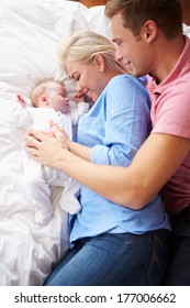 Parents Lying With Baby Girl In Bed Together