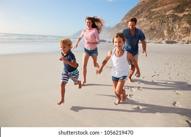 Parents Running Along Beach With Children On Summer Vacation