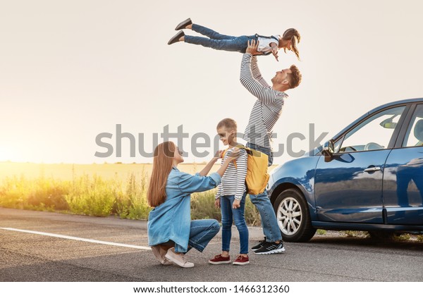 Parents saying\
goodbye to their children near\
car