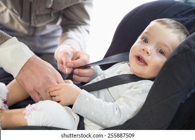 Parents Securing Baby In The Car Seat In His Car