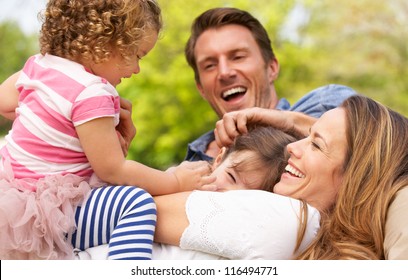 Parents Sitting With Children In Field Of Summer Flowers - Powered by Shutterstock