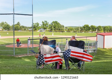 Parents Sitting In Folding Chairs Watching A High School Baseball Game