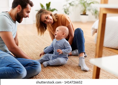 Parents Sitting On Floor At Home Playing With Baby Son