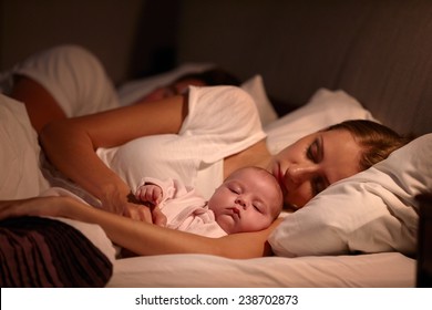 Parents Sleeping In Bed With Newborn Baby