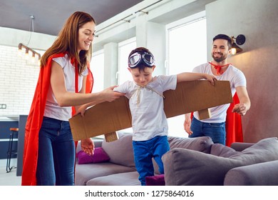 Parents and son in a superhero costume play in a room. - Powered by Shutterstock