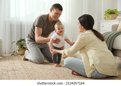 Parents supporting their baby daughter while she learning to walk at home - Powered by Shutterstock