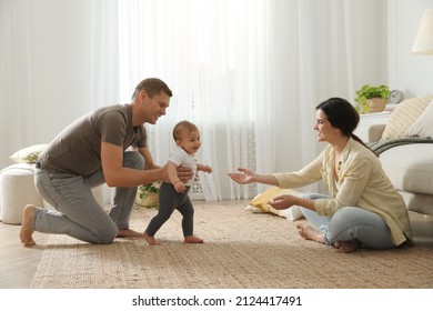 Parents supporting their baby daughter while she learning to walk at home - Powered by Shutterstock