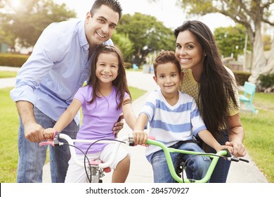 Parents Teaching Children To Ride Bikes In Park