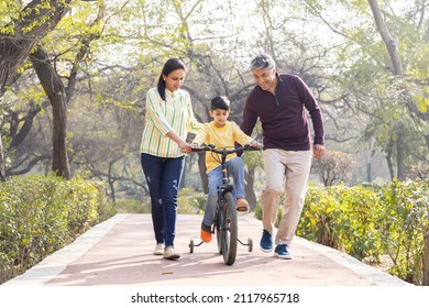 Parents Teaching Son Riding Bicycle At Park