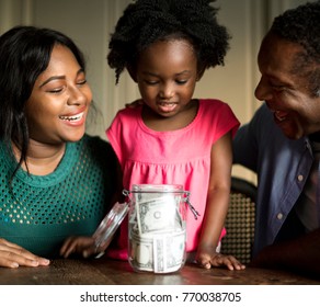 Parents Teaching Their Daughter On How To Save Money