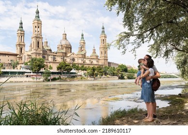 Parents and their baby at the riverbank of Ebro   in front of Basilica del Pilar in Zaragoza. Family tourism in Europe.