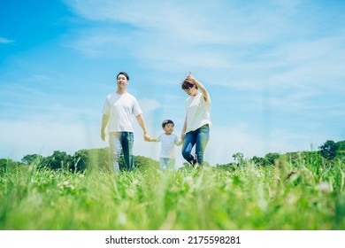 parents and their child holding hands and walking in a sunny green space - Powered by Shutterstock