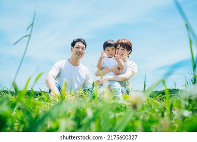 Parents And Their Child Sitting On A Sunny Green Space
