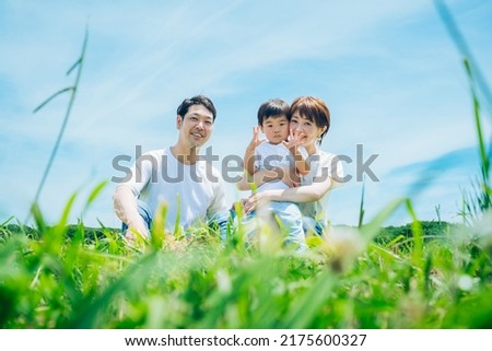 Parents and their child sitting on a sunny green space