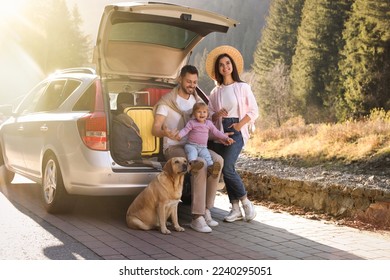 Parents, their daughter and dog near car outdoors. Family traveling with pet - Shutterstock ID 2240295051
