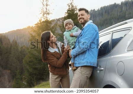 Parents and their daughter near car in mountains. Family traveling
