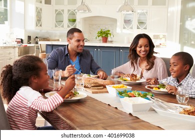 Parents and their two children eating at kitchen table