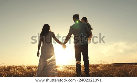 Parents walking hand in hand with father carrying daughter. Silhouettes of parents walk with hands entwined and father holds daughter. Parents joining hands with father carrying daughter