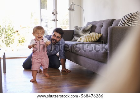 Parents Watching Baby Daughter Take First Steps At Home