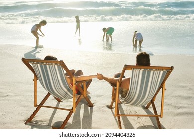 Parents watching children play on beach