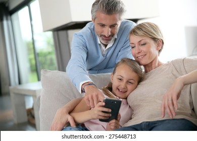 Parents watching daughter playing with smartphone  - Powered by Shutterstock