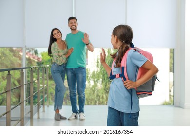 Parents Waving Goodbye To Their Daughter In School