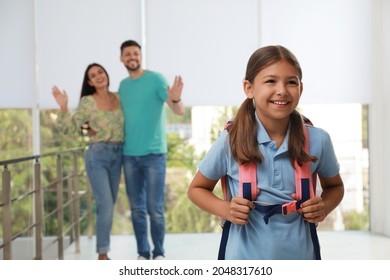 Parents Waving Goodbye To Their Daughter In School