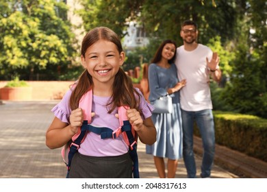 Parents Waving Goodbye To Their Daughter Before School Outdoors