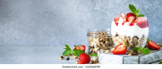 Parfait with cream or yogurt, jam and fresh strawberries in the glass jar.