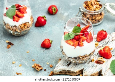 Parfait with fresh fruit, greek yogurt, oat granola, honey and mint leaves in glass jar on a wooden board. gluten free diet, Healthy breakfast. place for text, top view,