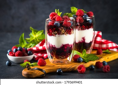 Parfait with yogurt, granola, jam and fresh berries in the glass jar. Healthy dessert or snack.