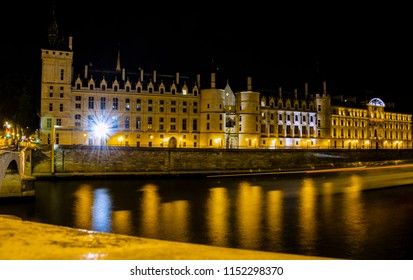 Paris By Night (France). The Seine And The Conciergerie In The Background. The Wake Of A Boat Darting Across The River. Photo Taken With Long Exposure.