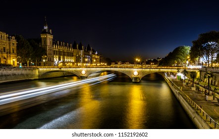 Paris By Night. The Seine And The City In The Background. On The Left The Wake Of A Boat Darting Across The River. Photo Taken With Long Exposure.