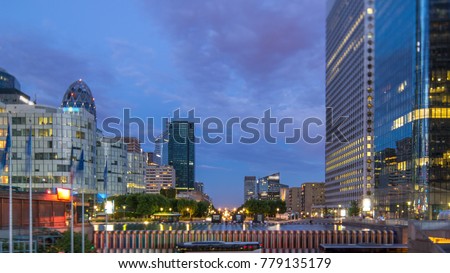 Paris cityscape with modern buildings in business district La Defense day to night transition timelapse. Glass facade skyscrapers. Arc de Triomphe with Champs Elysees on background. Concept of