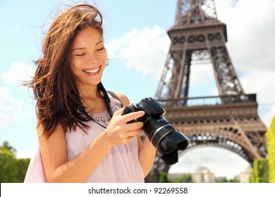 Paris Eiffel Tower tourist with camera taking pictures in front of the Eiffel tower, Paris, France. Young photographer woman in her 20s.