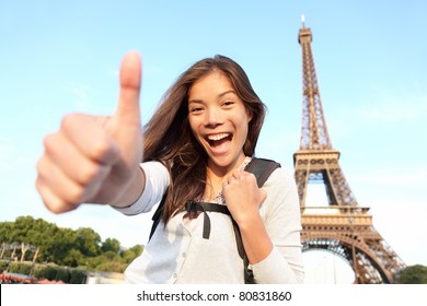 Paris Eiffel Tower Tourist Happy Backpacking In Europe. Cheerful Smiling Woman Tourist Showing Thumbs Up Success Sign In Front Of Eiffel Tower, Paris. Beautiful Asian Caucasian Female Model.