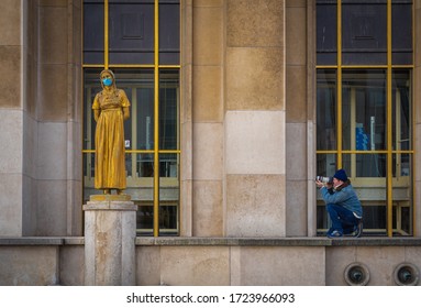 Paris, France - 05 06 2020: The photographer and the golden statue of a woman wearing a surgical mask during confinement against coronavirus and the eiffel tower